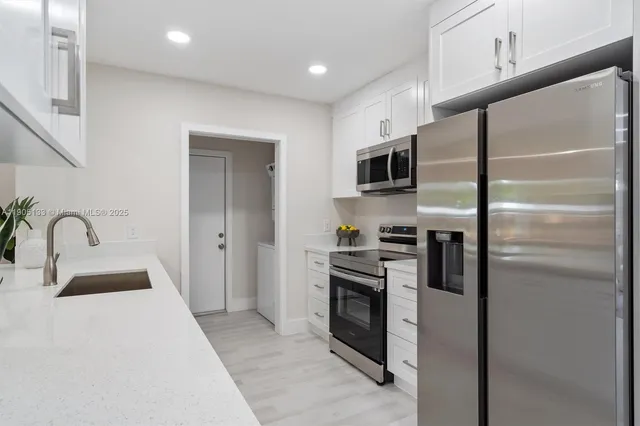 a kitchen with stainless steel appliances kitchen island granite countertop a stove a sink and a refrigerator