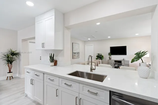 a kitchen with sink a potted plant and cabinets