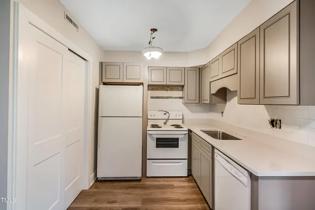 a kitchen with a sink a refrigerator and a stove top oven with wooden floor