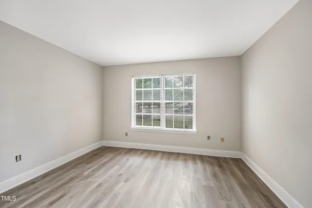 an empty room with wooden floor and window