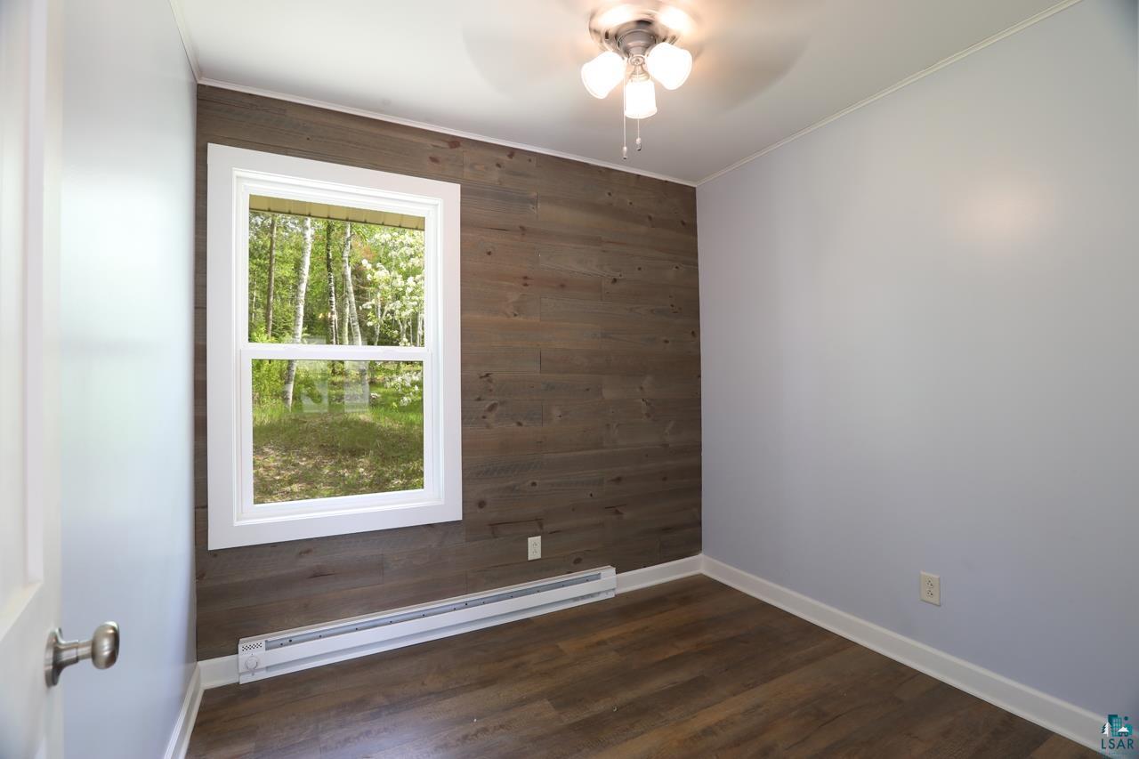 3739 Sundling Road Tower, MN 55790 - Photo 5 of 15 Empty room with wood walls, baseboard heating, ceiling fan, and dark hardwood / wood-style floors