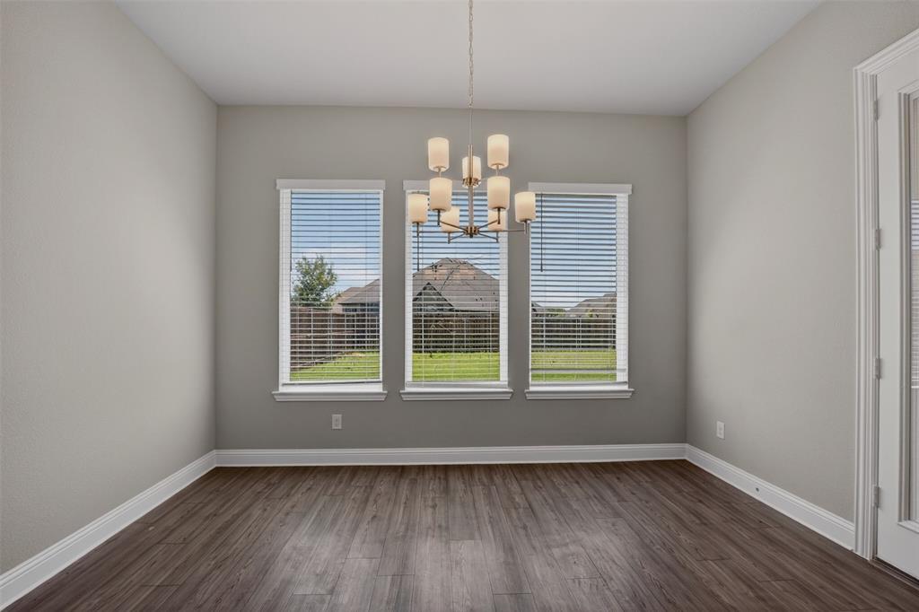 16812 Bitterroot Road Justin, TX 76247 - Photo 18 of 27 an empty room with wooden floor chandelier and windows