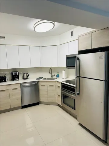 a kitchen with stainless steel appliances granite countertop a refrigerator sink and white cabinets