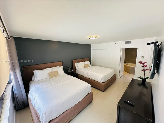 a bedroom with two beds and a flat screen tv