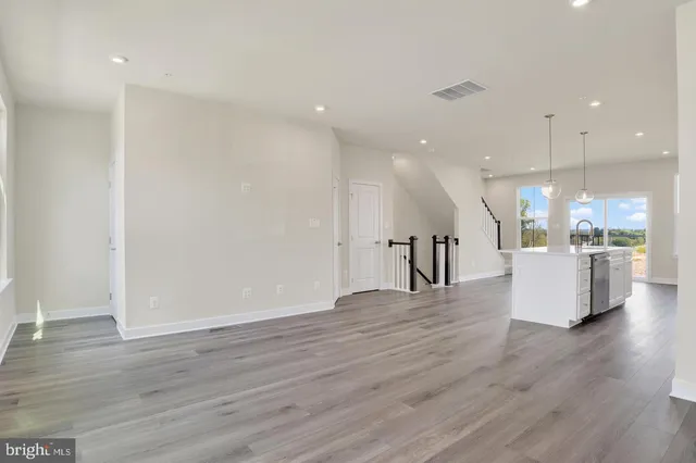 a kitchen with stainless steel appliances granite countertop a stove a sink a refrigerator and a wooden floor