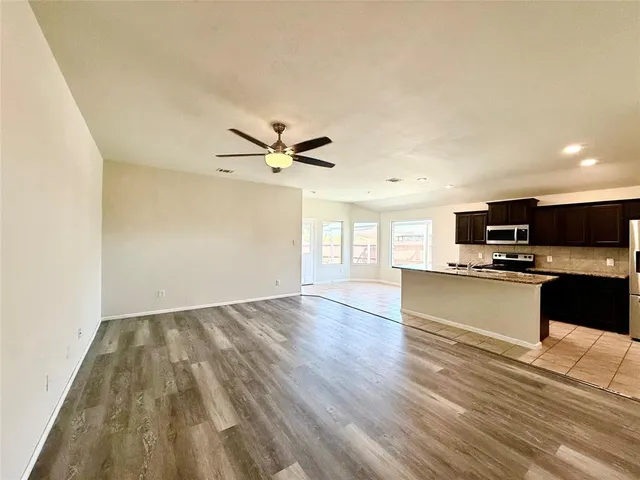 an empty room with a window and a ceiling fan