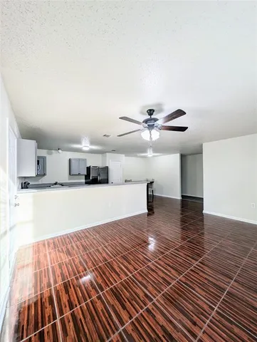 a view of kitchen and empty room with wooden floor