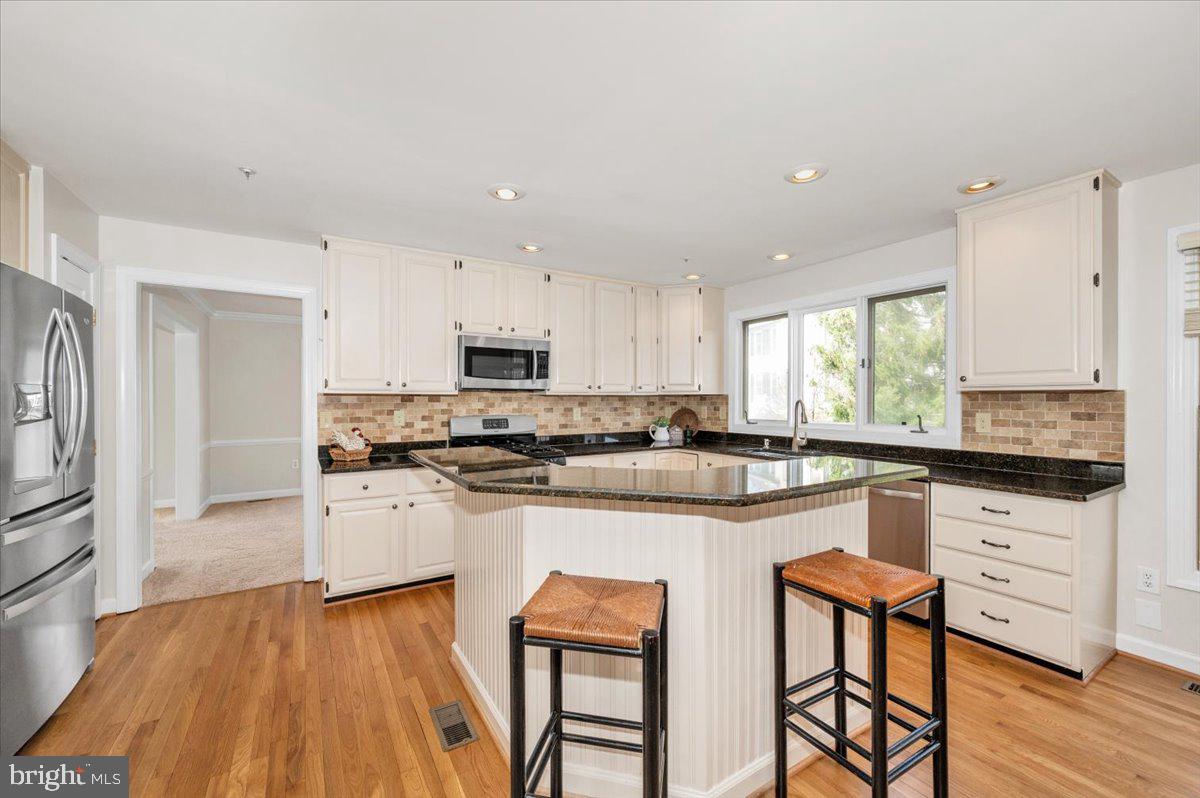 17900 Hickman Street Poolesville, MD 20837 - Photo 14 of 97 a kitchen with stainless steel appliances granite countertop a stove top oven a sink dishwasher and a refrigerator with wooden floor