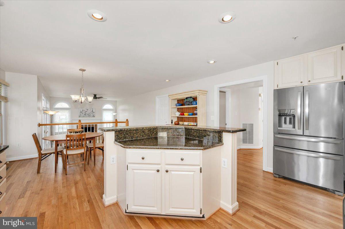 17900 Hickman Street Poolesville, MD 20837 - Photo 18 of 97 a kitchen with stainless steel appliances kitchen island granite countertop a refrigerator a stove a dining table and chairs with wooden floor