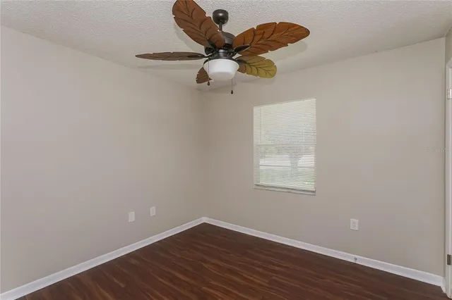 a view of a room with wooden floor ceiling fan and window