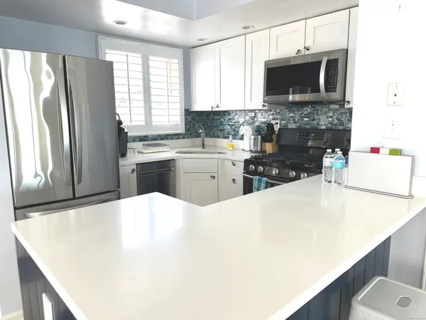 a view of a kitchen with kitchen island a large window a sink and living room view