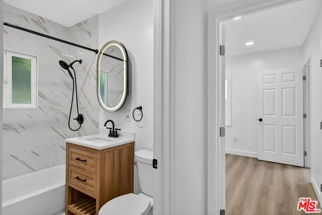 a bathroom with a sink vanity mirror and tub