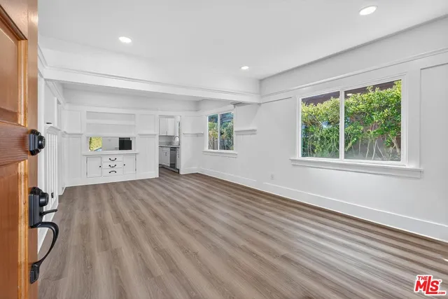 a view of empty room with wooden floor and window