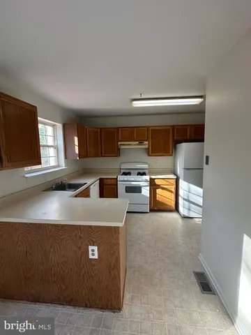 a living room with stainless steel appliances kitchen island granite countertop a refrigerator stove and sink