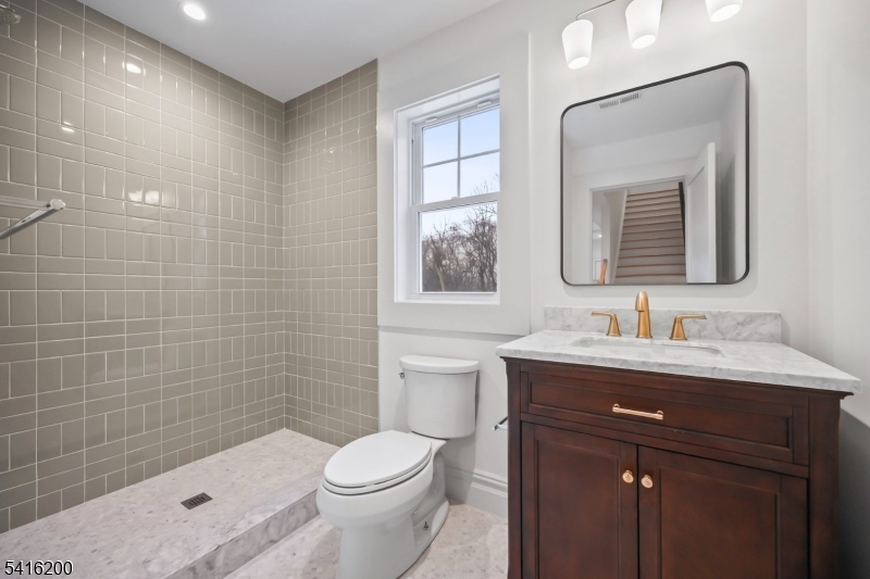 1209 Littleton Road, Unit D Morris Plains, NJ 07950 - Photo 20 of 23 a bathroom with a granite countertop toilet a sink a mirror and shower