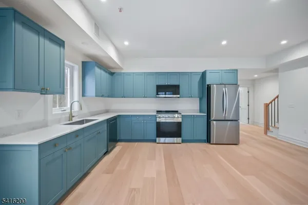 a large kitchen with stainless steel appliances a sink and a refrigerator