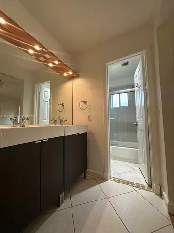 a bathroom with a vanity a sink a mirror and a shower