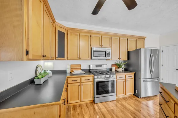 a kitchen with stainless steel appliances granite countertop a refrigerator a stove a sink dishwasher and white countertops with wooden floor