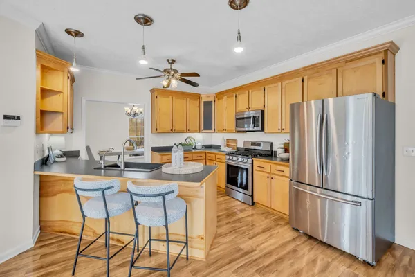 a kitchen with stainless steel appliances granite countertop a refrigerator a stove a sink dishwasher a dining table and chairs with wooden floor