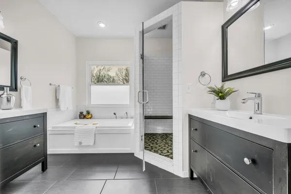 a bathroom with a double vanity sink mirror and bathtub