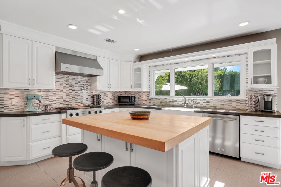16722 Adlon Road Encino, CA 91436 - Photo 11 of 36 a kitchen with a stove a sink a kitchen island and chairs in it
