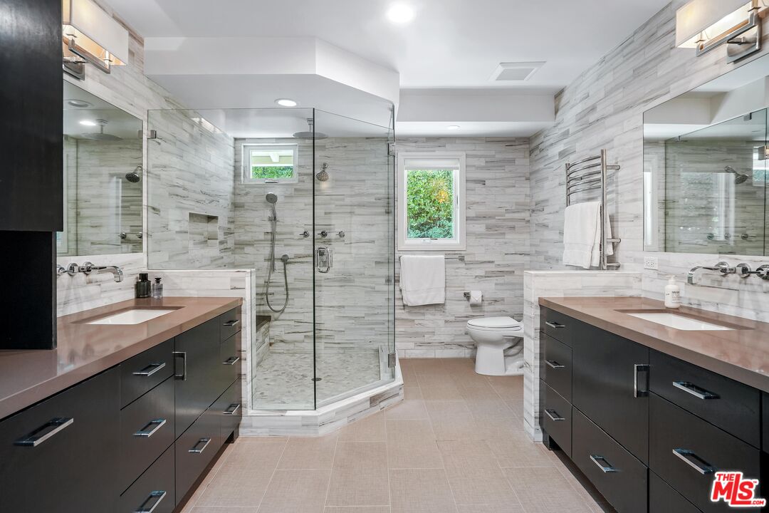 16722 Adlon Road Encino, CA 91436 - Photo 17 of 36 a spacious bathroom with a granite countertop sink a toilet a shower and a mirror