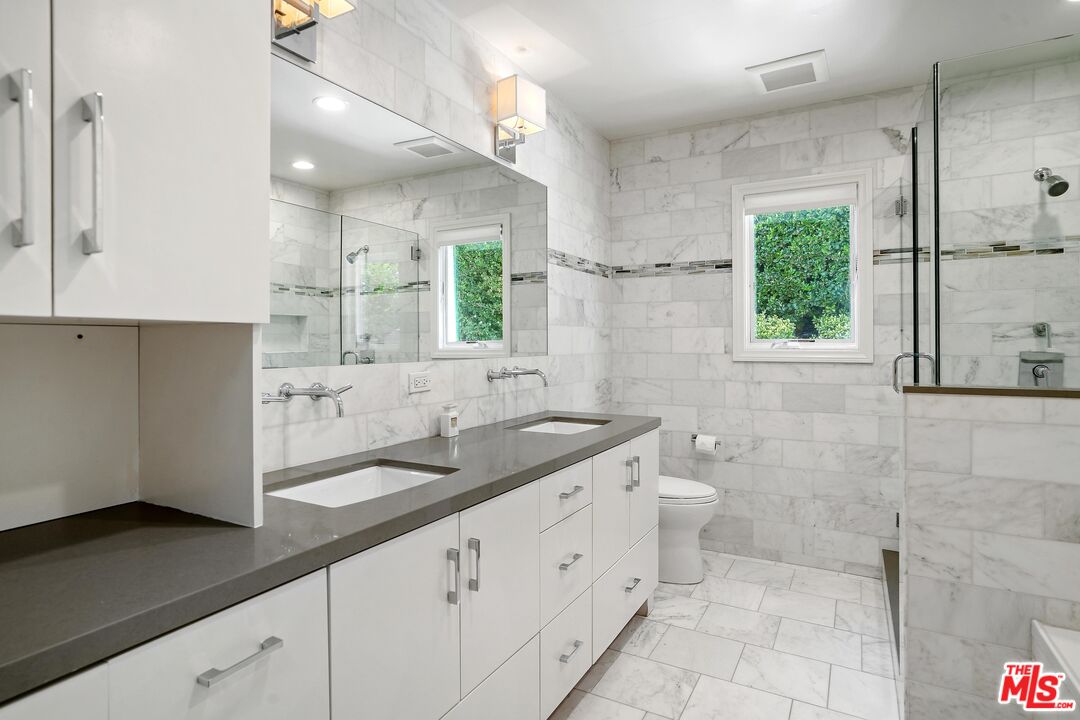 16722 Adlon Road Encino, CA 91436 - Photo 20 of 36 a bathroom with a double vanity sink a mirror and a shower