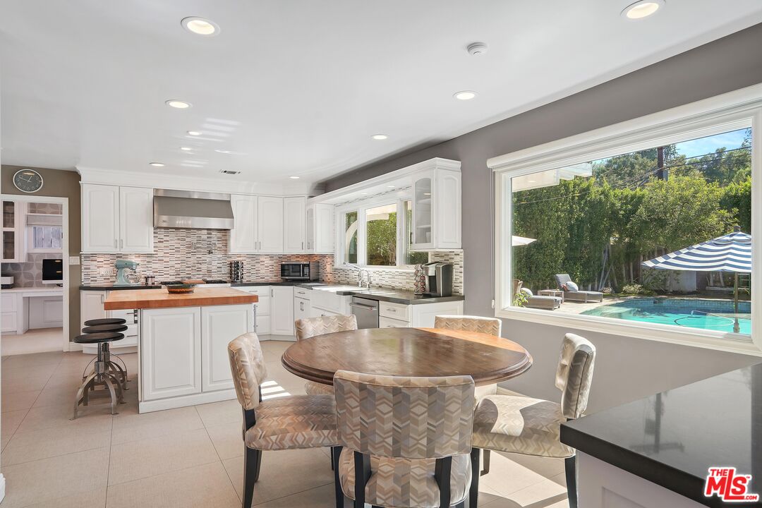 16722 Adlon Road Encino, CA 91436 - Photo 9 of 36 a large kitchen with kitchen island a large window in a dining table and chairs