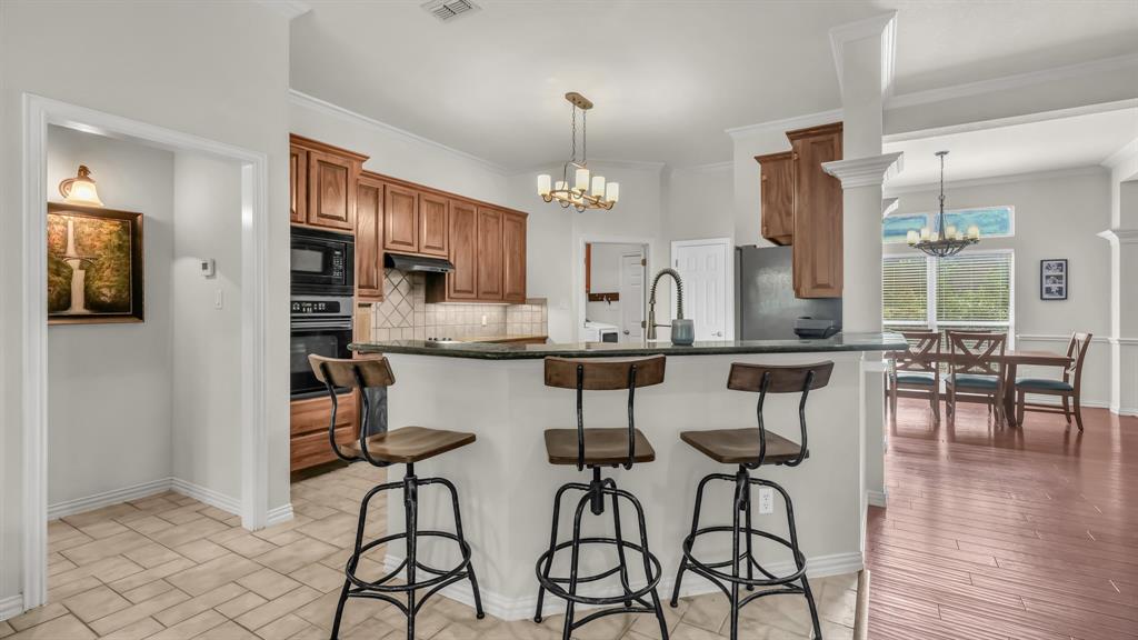 203 Mockingbird Lane Aledo, TX 76008 - Photo 16 of 37 Kitchen featuring a breakfast bar with dark countertops, wood cabinetry, and stainless steel double ovens