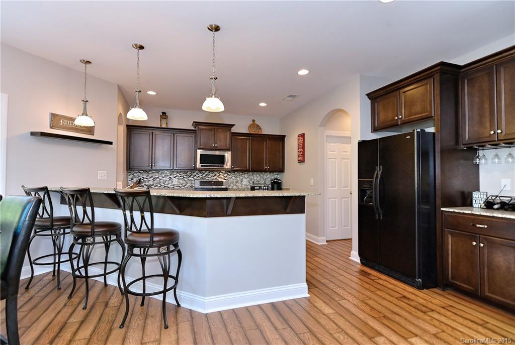3321 Bridgewick Road Waxhaw, NC 28173 - Photo 5 of 24 a kitchen with stainless steel appliances granite countertop a refrigerator a stove top oven a sink dishwasher a dining table and chairs with wooden floor