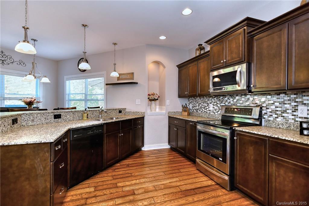 3321 Bridgewick Road Waxhaw, NC 28173 - Photo 6 of 24 a large kitchen with stainless steel appliances granite countertop a stove a sink dishwasher and a microwave oven with wooden cabinets