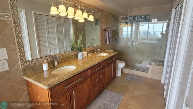 a bathroom with a granite countertop sink a toilet a mirror and shower