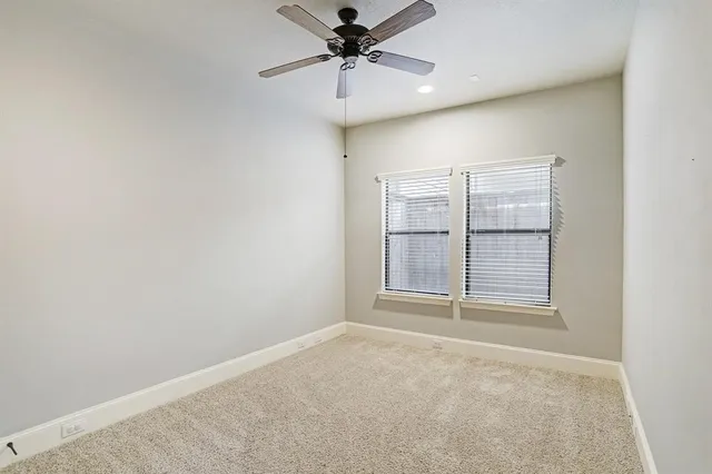 an empty room with chandelier fan and windows