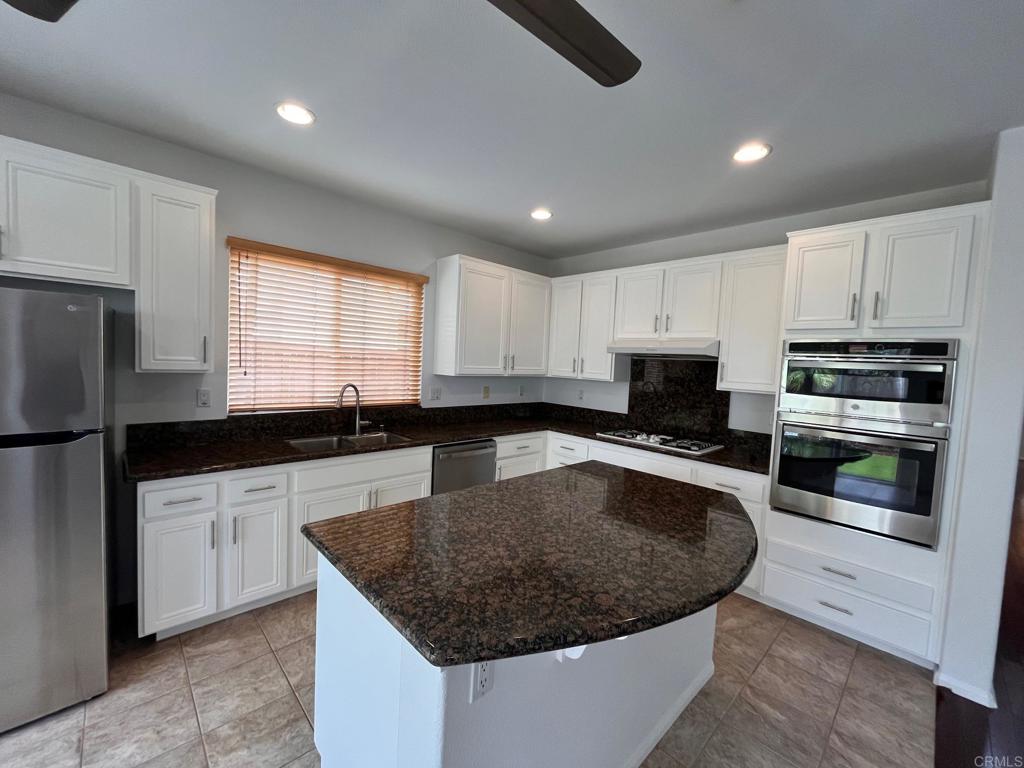 3840 Stoneridge Road Carlsbad, CA 92010 - Photo 13 of 36 a kitchen with stainless steel appliances granite countertop a sink a stove a microwave a center island and a refrigerator