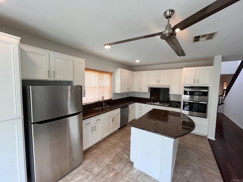 3840 Stoneridge Road Carlsbad, CA 92010 - Photo 14 of 36 a kitchen with granite countertop a refrigerator a sink a stove and white cabinets