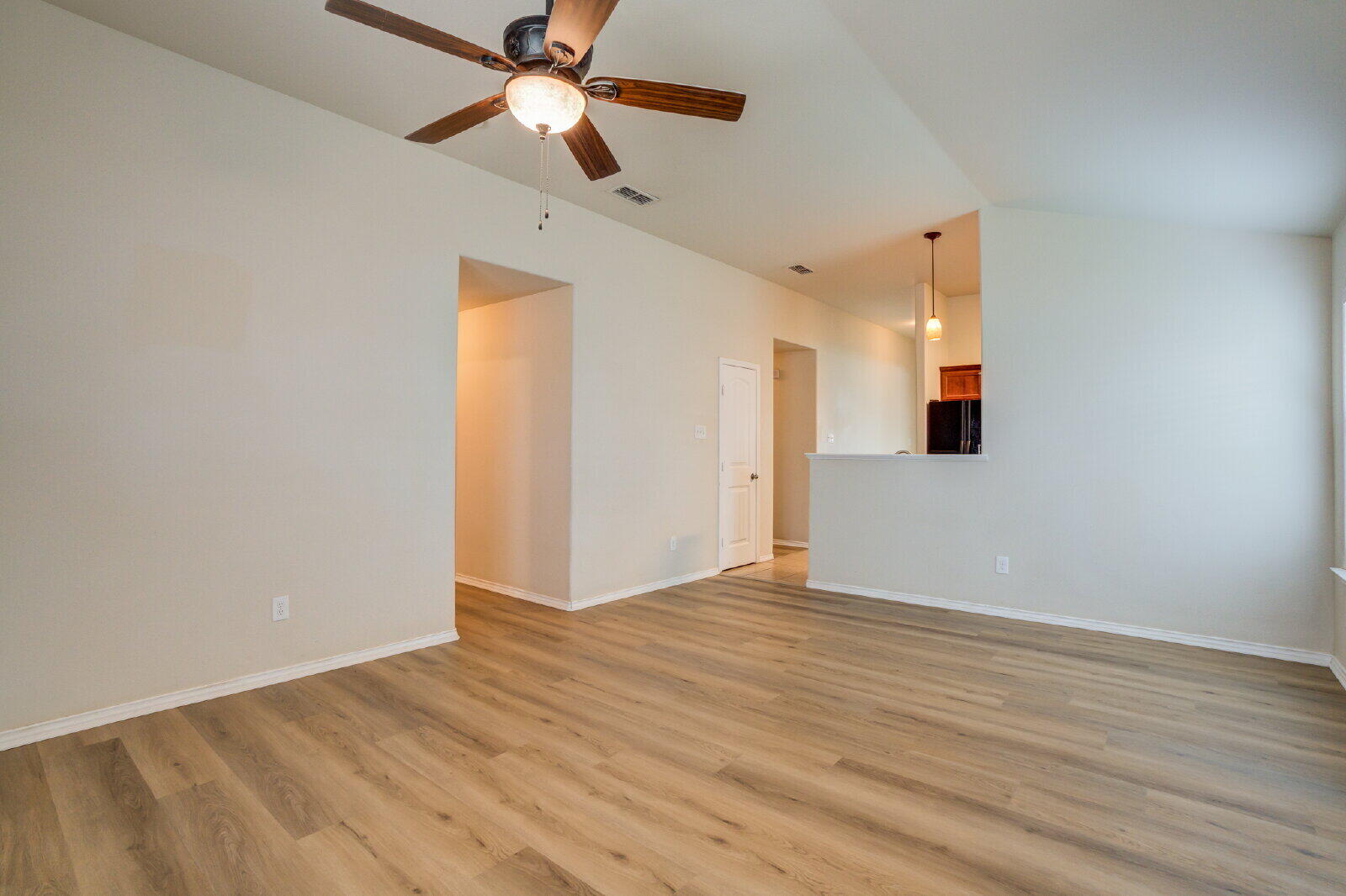 6921 95th Street Lubbock, TX 79424 - Photo 15 of 32 an empty room with wooden floor ceiling fan and windows