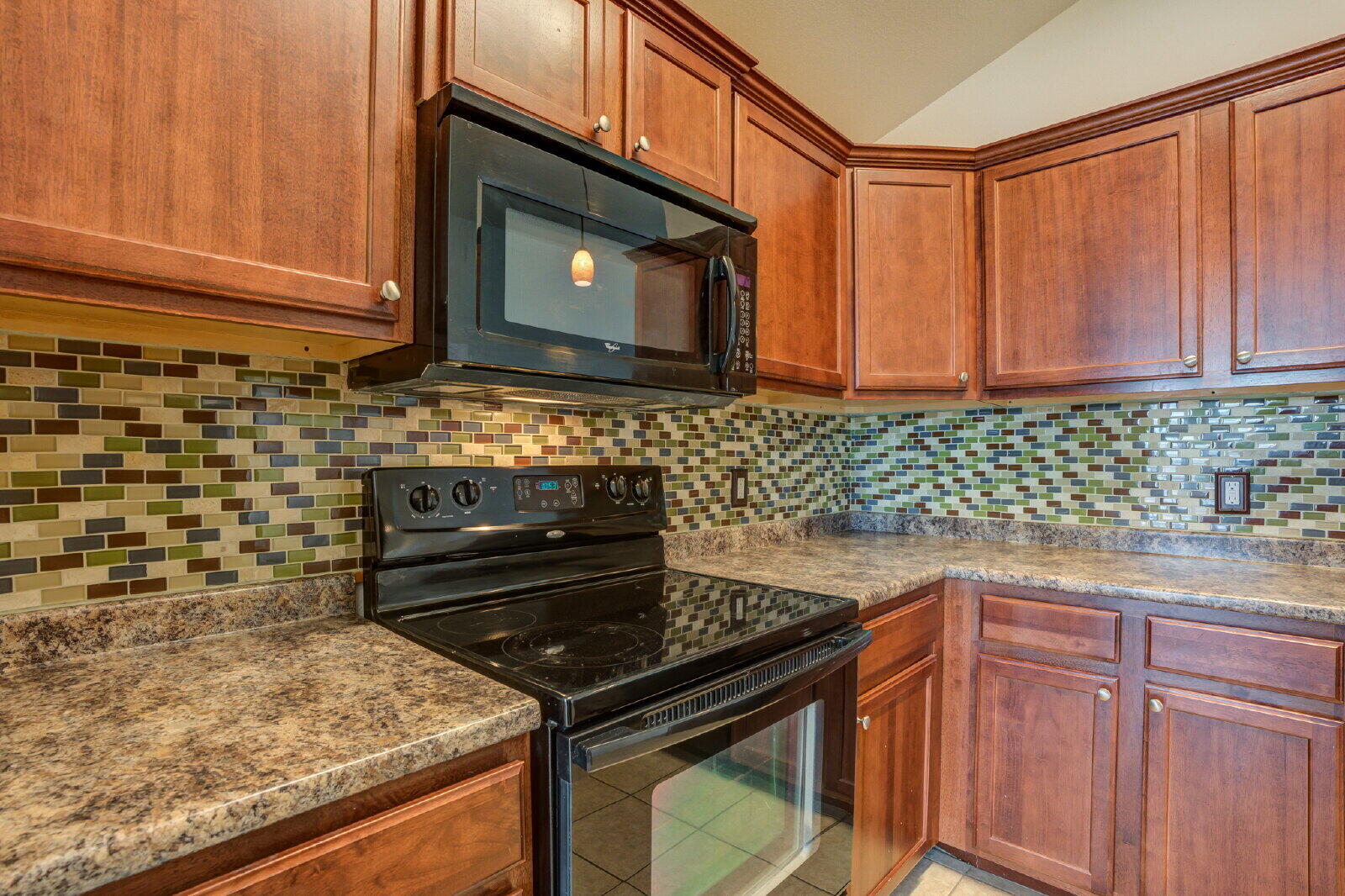 6921 95th Street Lubbock, TX 79424 - Photo 8 of 32 a kitchen with granite countertop a stove top oven microwave and cabinets