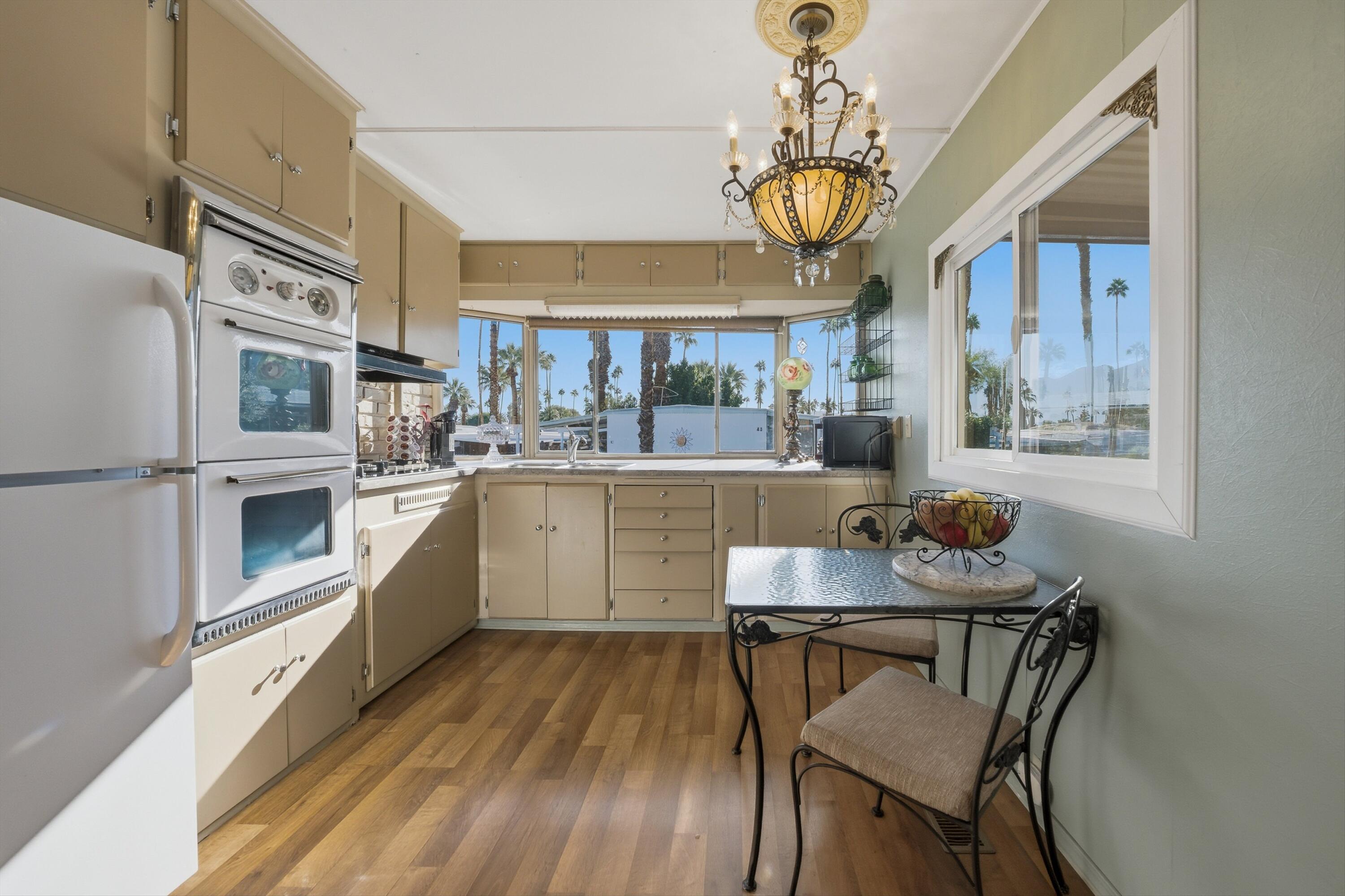 70260 Highway 111, Unit 42 Rancho Mirage, CA 92270 - Photo 19 of 35 a kitchen with stainless steel appliances granite countertop a stove top oven a dining table and chairs with wooden floor