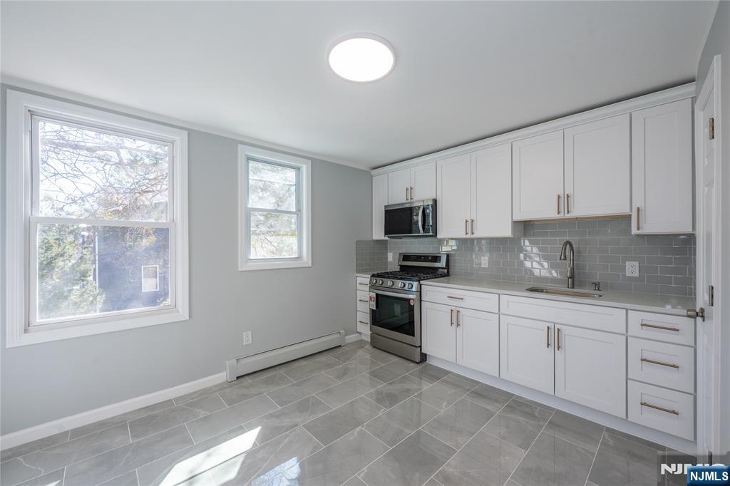 723 East 26th Street Paterson, NJ 07504 - Photo 30 of 41 a kitchen with stainless steel appliances granite countertop a stove top oven a sink a window and white cabinets