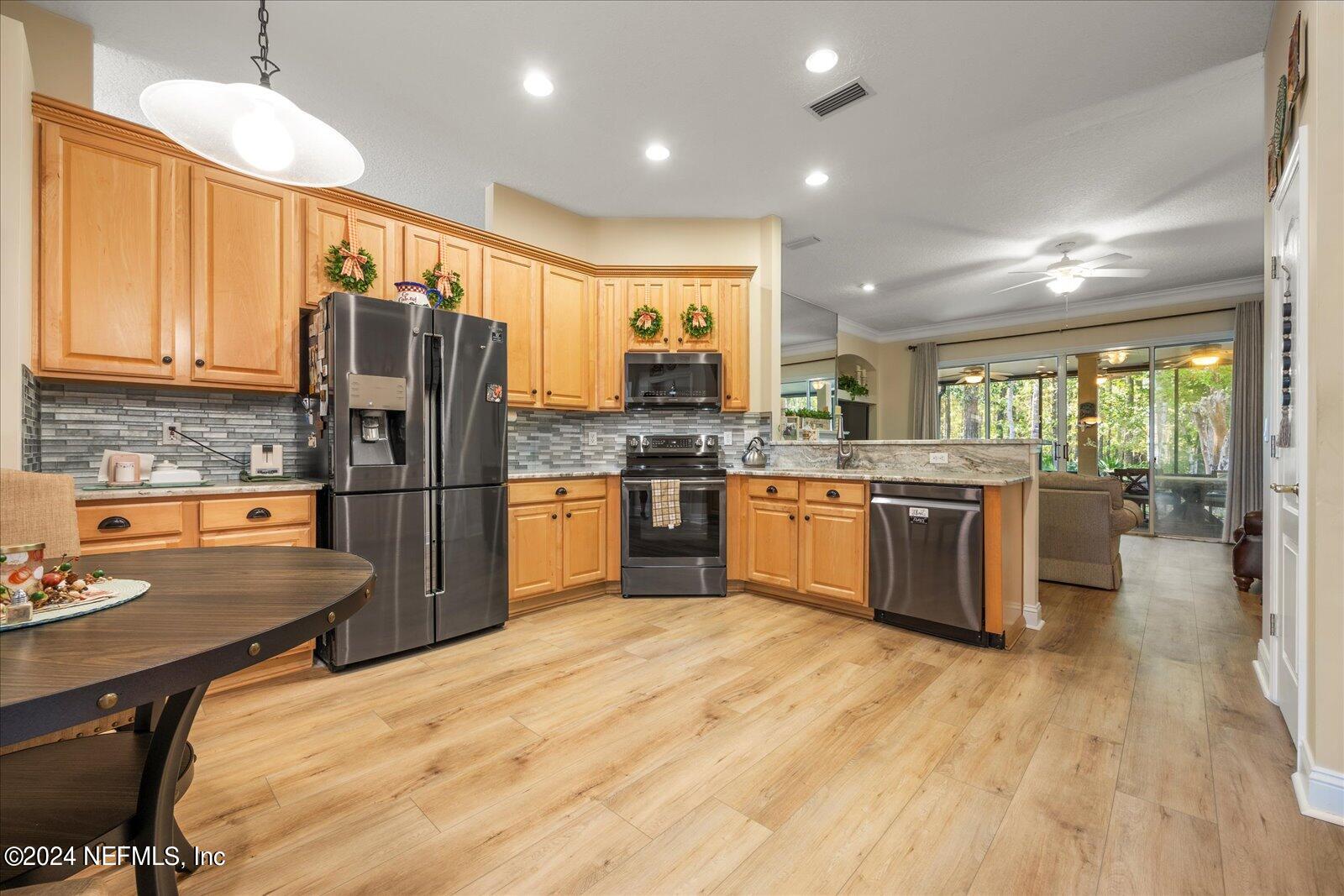 1283 Paradise Pond Road St. Augustine, FL 32092 - Photo 12 of 47 a kitchen with stainless steel appliances granite countertop a refrigerator a stove top oven a sink dishwasher and white cabinets with wooden floor