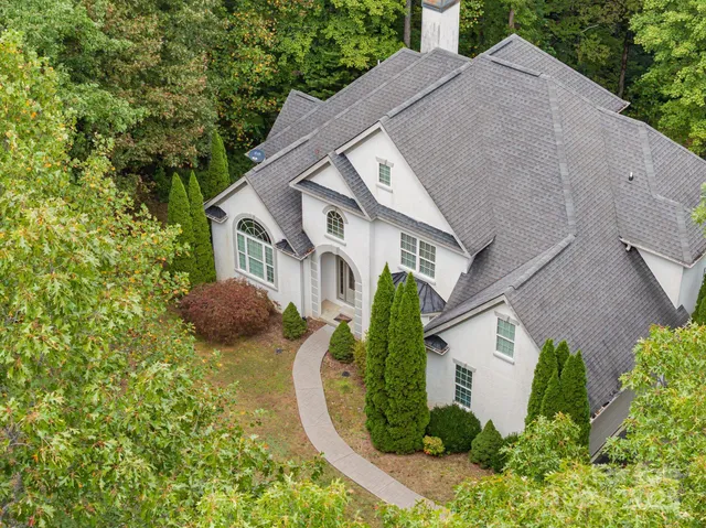 an aerial view of a house with swimming pool and large trees