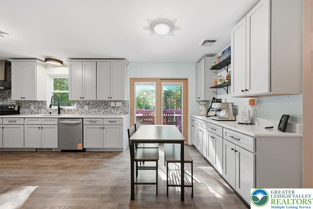 128 Chestnut Street Dingmans Ferry, PA 18328 - Photo 7 of 43 Step into this contemporary kitchen, featuring extensive cabinetry, sleek countertops, and a clear view to the outdoors.