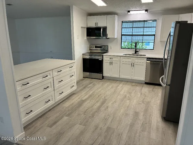 a kitchen with granite countertop a refrigerator stove and sink