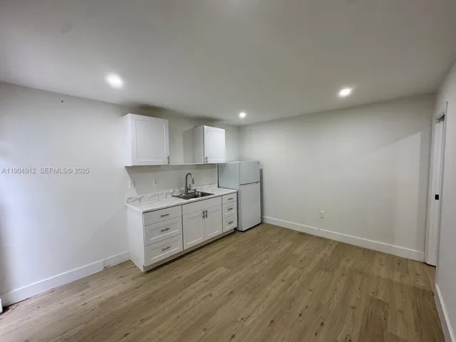 a kitchen with granite countertop white cabinets and wooden floor