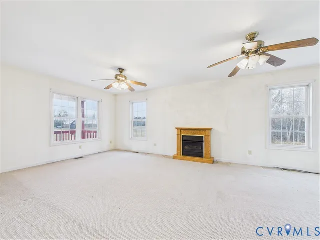 an empty room with windows and ceiling fan
