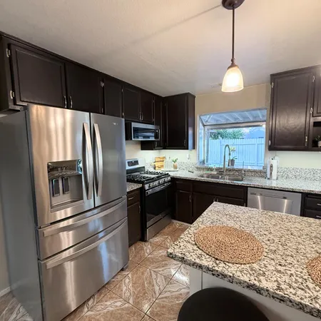 a kitchen with stainless steel appliances granite countertop a refrigerator a stove a sink and a refrigerator