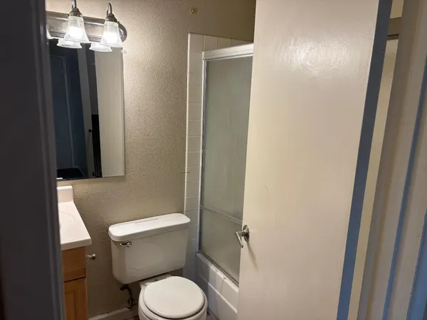 a white toilet sitting next to a shower
