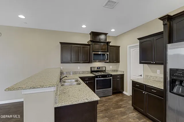 a kitchen with stainless steel appliances granite countertop a sink stove microwave and refrigerator