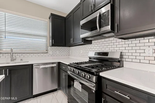 a kitchen with stainless steel appliances a sink stove and microwave