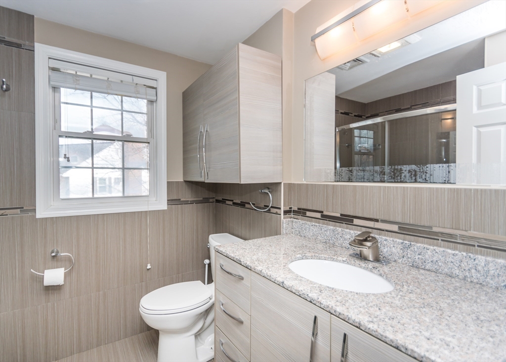 985 Trapelo Road, Unit 23 Waltham, MA 02452 - Photo 20 of 27 a bathroom with a granite countertop toilet sink and mirror
